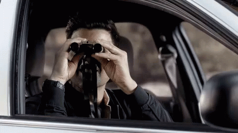 man looking into a car rear view mirror