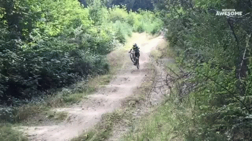 a dirt road that has a man riding a bike