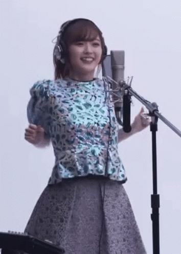 an asian girl wearing headphones is singing in front of microphone