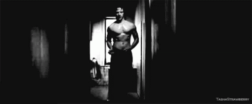 black and white pograph of shirtless man in hallway