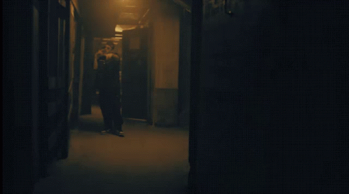 an hallway that has a man walking down the hall, and a blue light in the dark