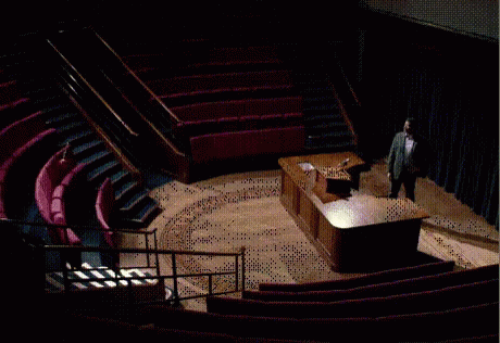 a man standing at a podium in front of an empty auditorium