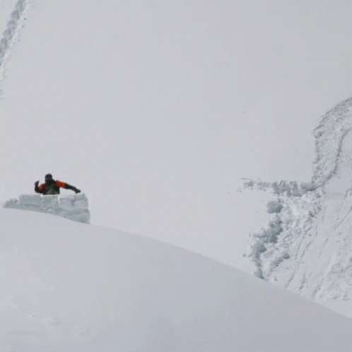 a man riding a snowboard down the side of a snow covered slope