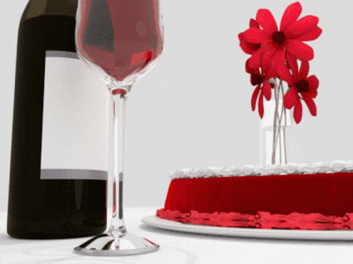 a cake with flowers sitting next to a wine bottle and wine glass