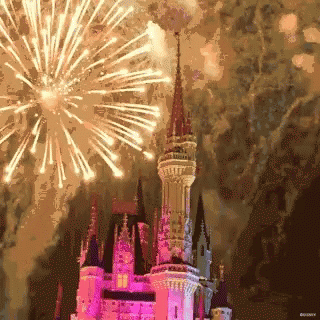 a castle with its lights on and fireworks in the sky