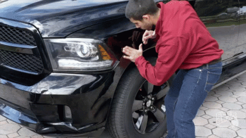 a man is fixing the front bumper on his truck