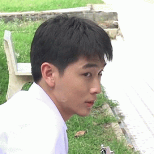 the face of an asian man sitting on a bench