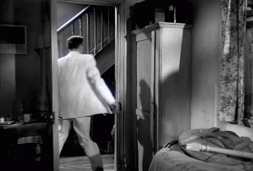 a man in a white suit looks in a doorway