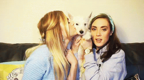 two women playing with a dog with blue make up on