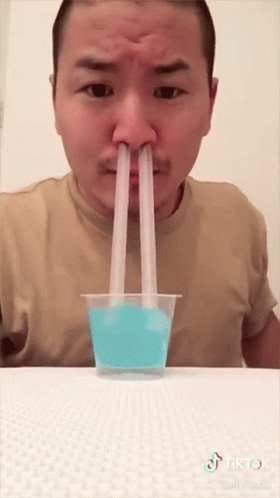 a man drinking from a sip of yellow liquid