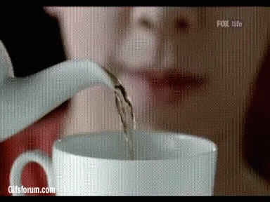 a white pitcher pouring water into a cup