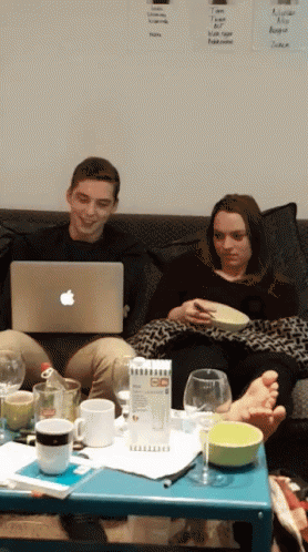 two girls and a guy are sitting on a couch while looking at their laptops