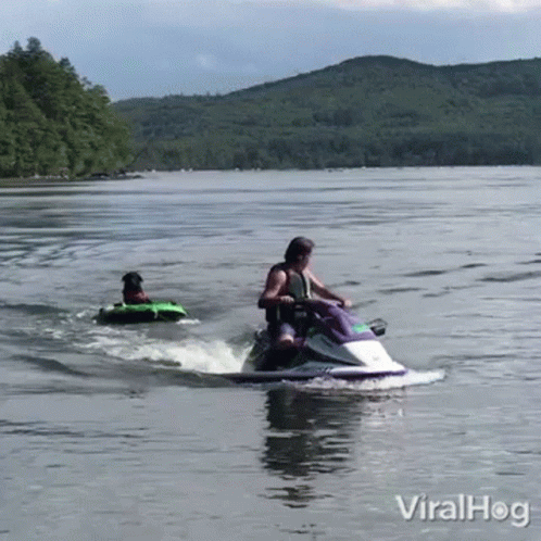 a woman in a blue shirt riding a jetski with people on the back