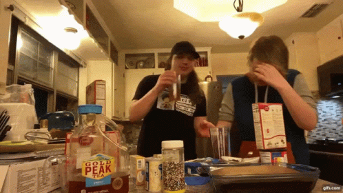 two people in the kitchen next to a counter covered in baking supplies