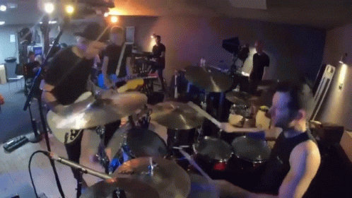 people playing drums in a band with blue lighting