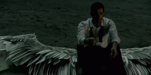 man in a shirt with white wings sitting on the ground
