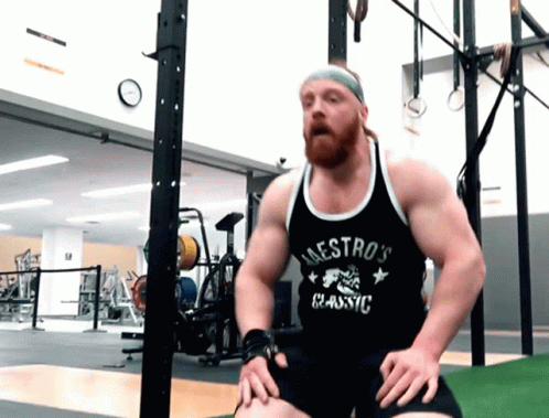 man squatting in gym with intense expression on face