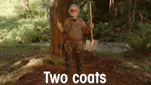 a man is standing in a dark forest with a shovel and wearing sunglasses