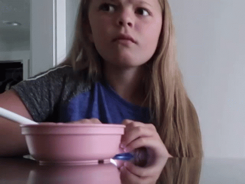 a girl with long hair looking surprised over a bowl