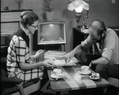 two people sitting around a table in front of a television