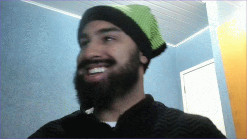 a man with a beard and wearing a knitted green hat