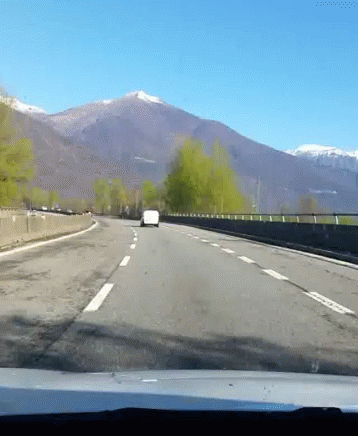 a car driving down the road in front of mountains