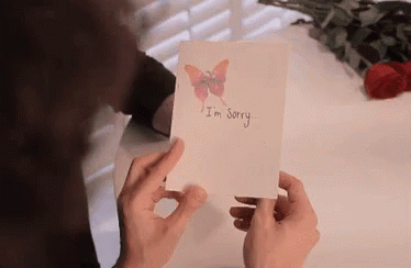 person holding up card with i'm sorry written on it