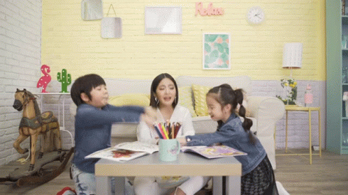 three young children sit at a table and look at soing in front of them
