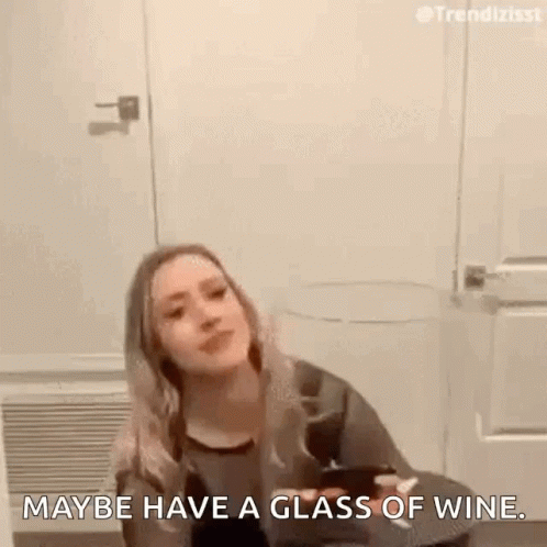 a woman is standing in front of a glass of wine