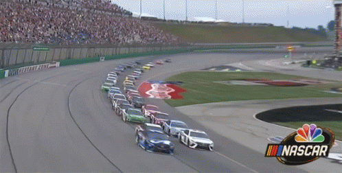 the nascar cars race along a track as people watch