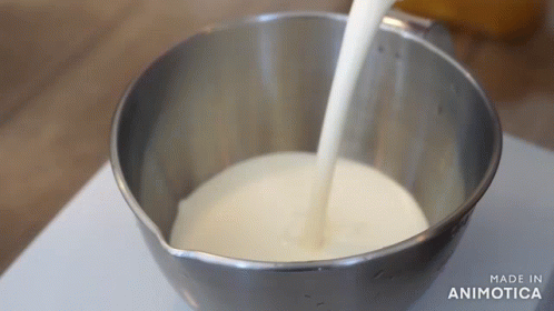 someone pours milk in a small bucket