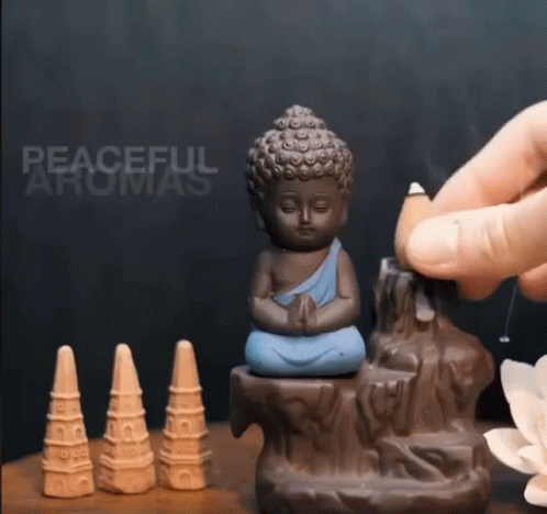 a hand is holding a small buddha statue