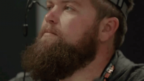 a bearded man wearing headphones is sitting down
