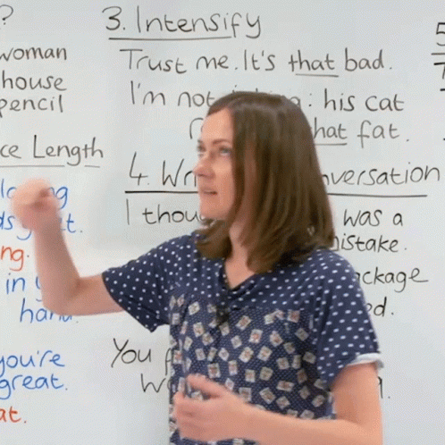 a woman standing in front of a whiteboard pointing up