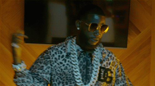 a man wearing an animal print jacket with sunglasses holding up soing