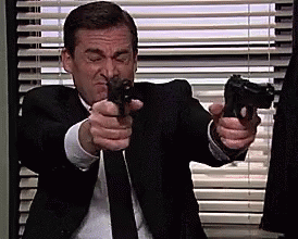 a man in a suit aiming a gun at another man