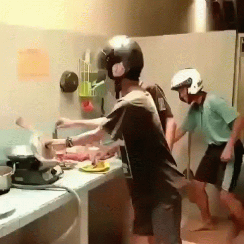 two children in helmet standing at a kitchen sink