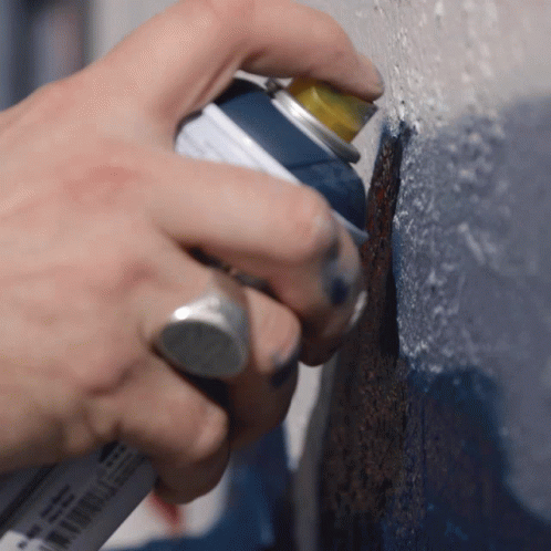 someone with blue gloves and latex gloves using paint to coat a wall