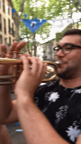 a man in blue with glasses is playing a trumpet