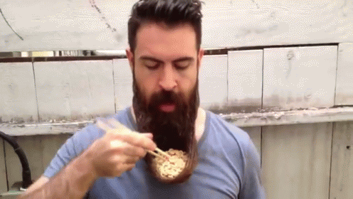 the bearded man is eating food while using the utensils