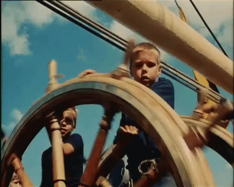 two young men looking around the wheels of a sailing vessel