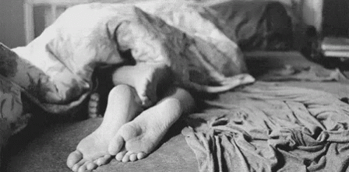 a black and white image of a person lying on their bed