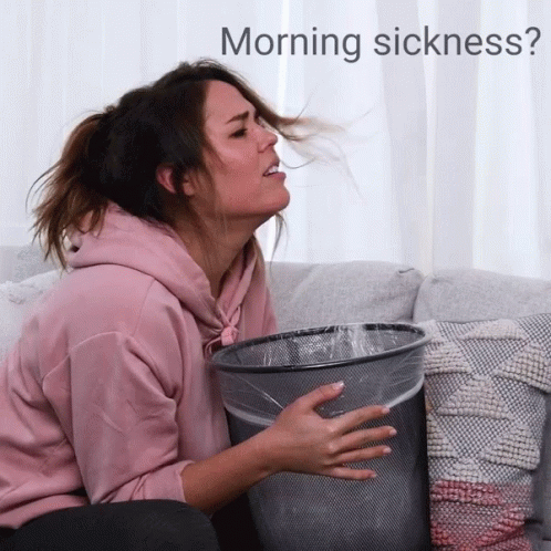 woman sitting on a couch holding a bucket and her face is shown with the word morning sickness?