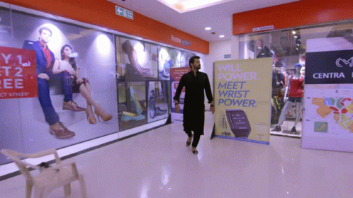 woman walks through a mall corridor in front of some posters