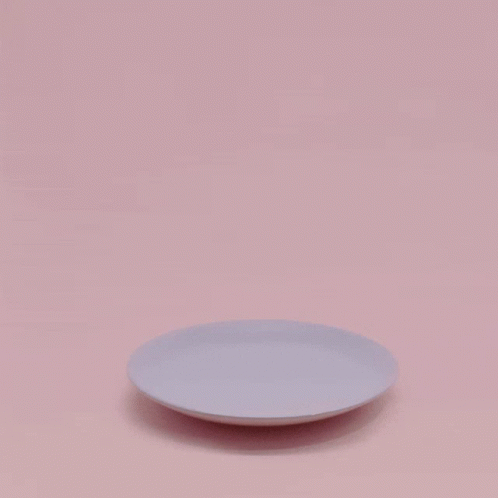 a white plate with a shadow of the table