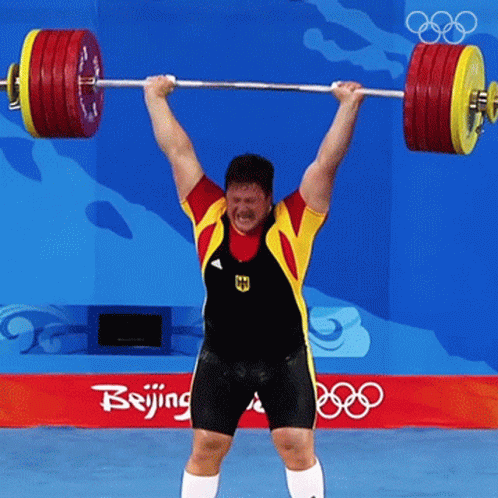 a man is holding two barbells over his shoulders