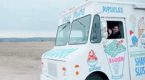 a man in an ice cream truck smiling and waving
