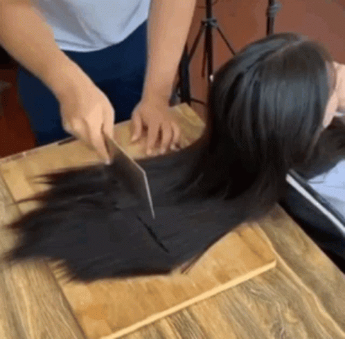 woman  her hair using a large pair of scissors
