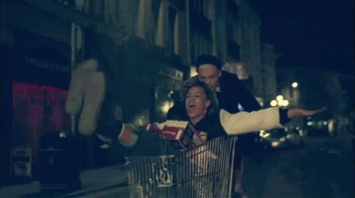 a woman with an umbrella rides in a shopping cart