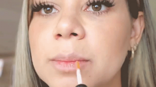 a blonde woman with a cigarette in her mouth and long eyelashes